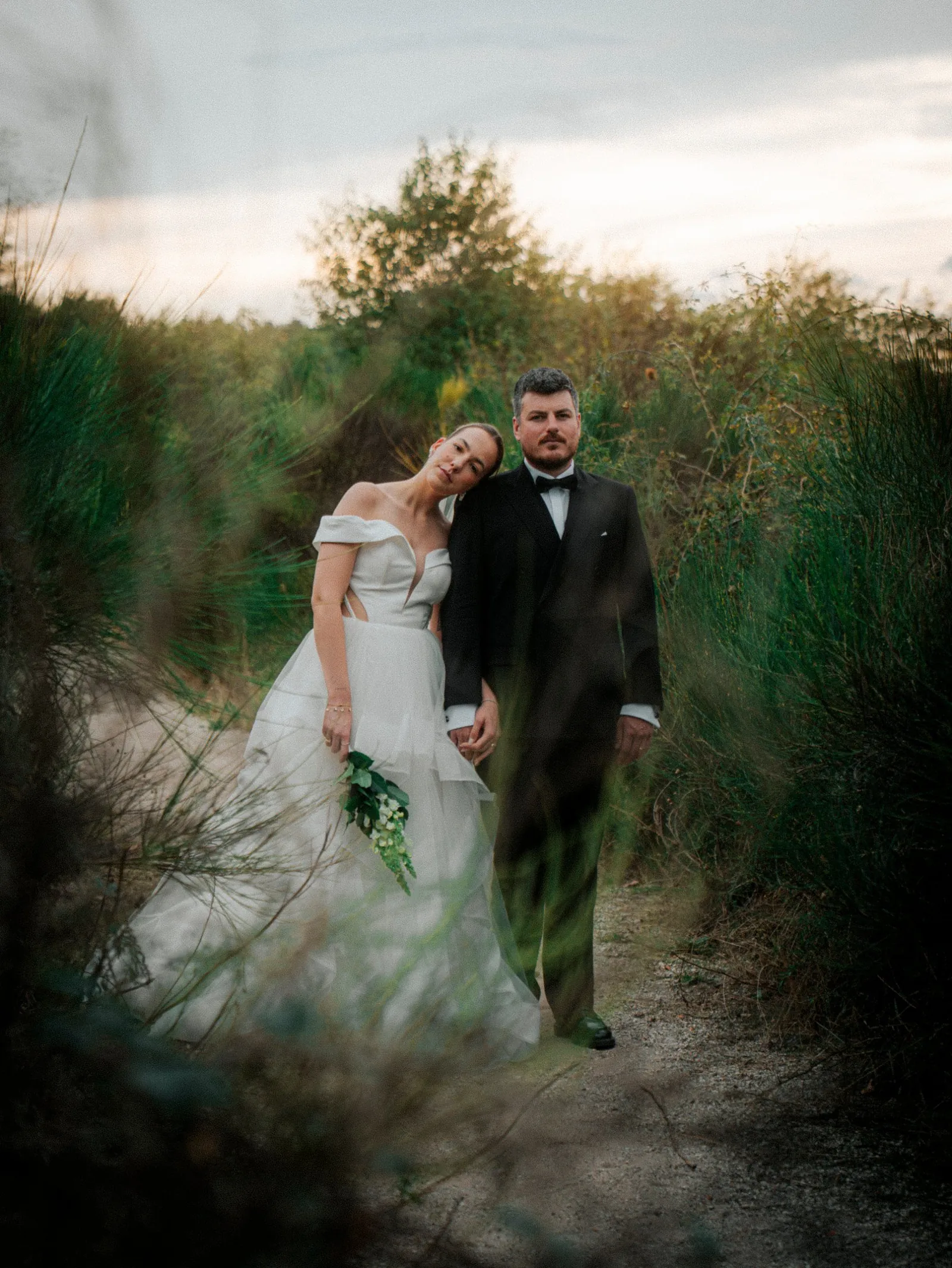 Hochzeitsfotografie NRW: Brautpaar auf einem Sandweg zwischen hohem Gras